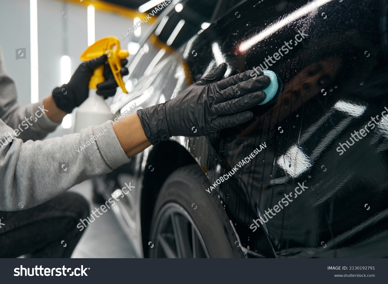 Experienced service station worker removing contaminants from automobile surface #2130192791