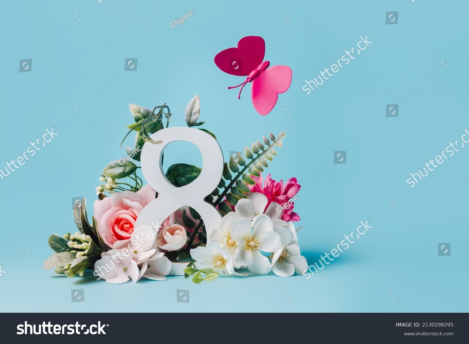 March 8th composition with number and flying butterfly and flowers against pastel blue background. Natural greeting banner for International Women's Day. Creative Mother's day floral concept. #2130298295