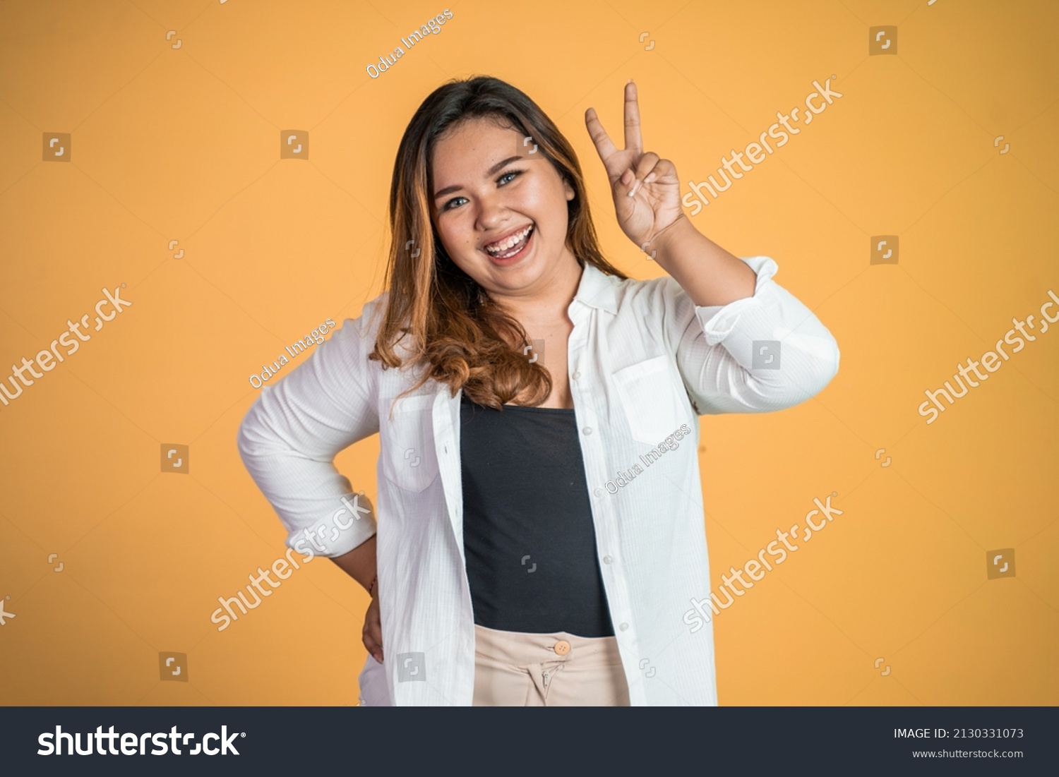 asian woman with cute hand gesture making v shape on finger #2130331073
