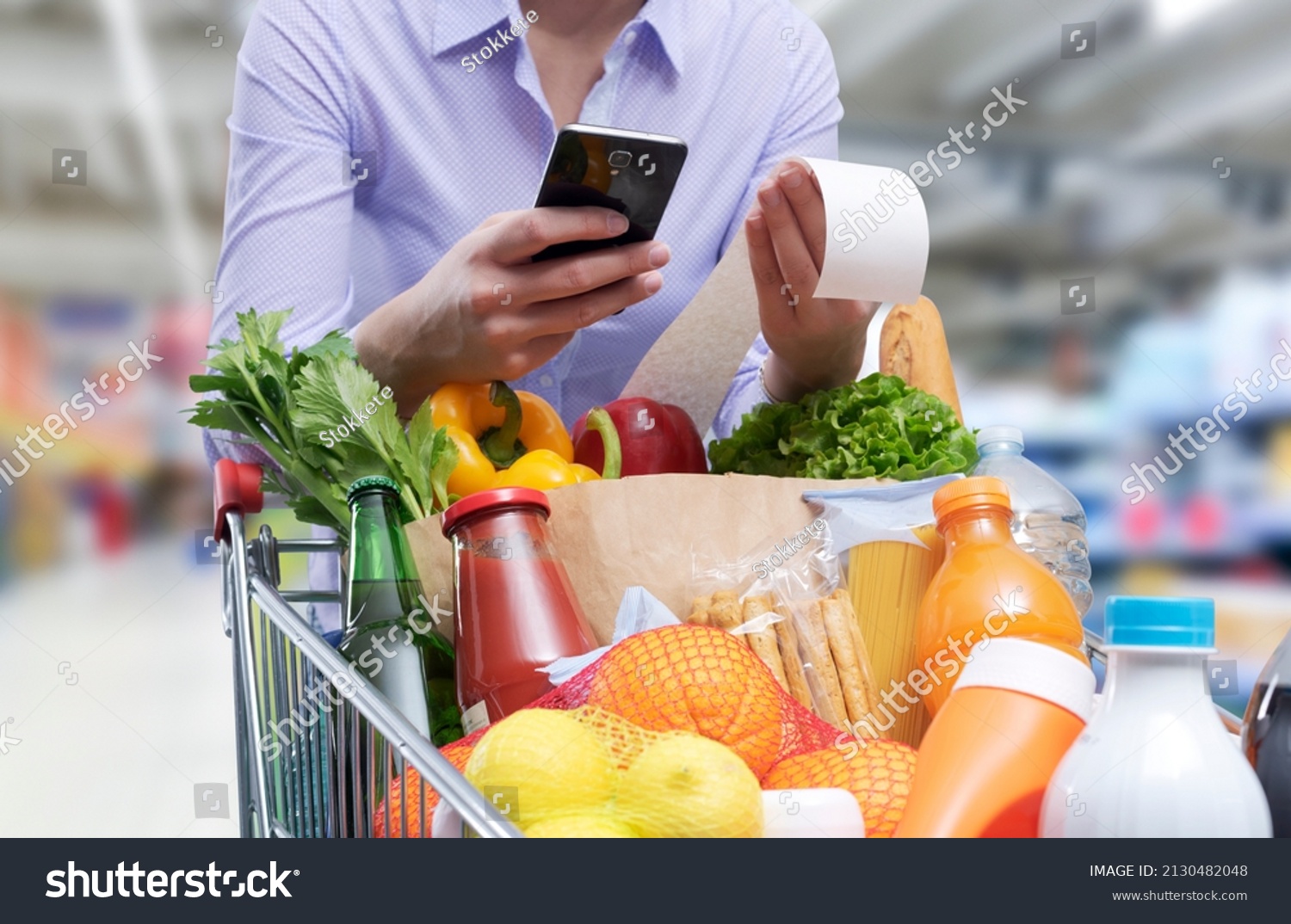 Woman checking the grocery receipt using her smartphone #2130482048