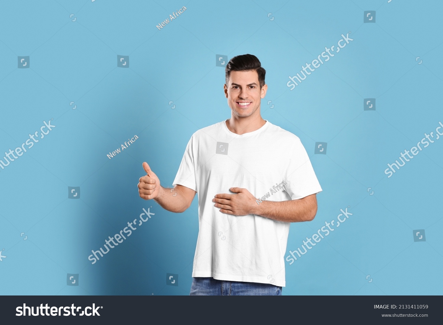 Happy healthy man touching his belly on light blue background #2131411059