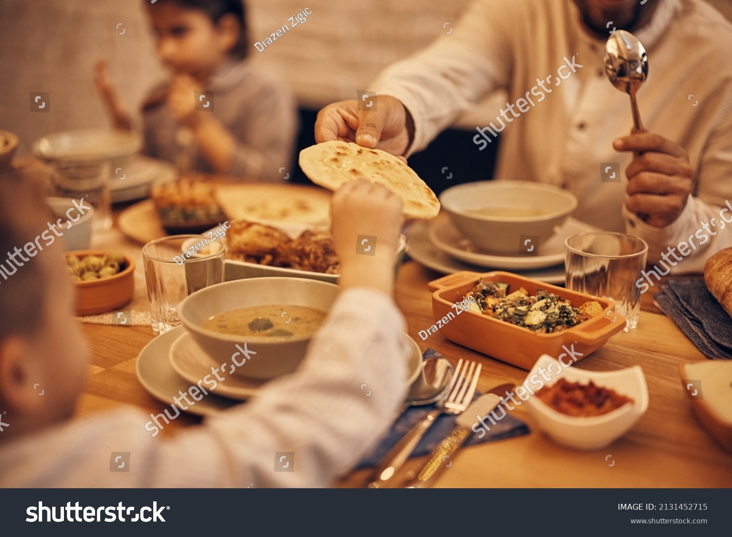 Close-up of Muslim father passing his son Lafah Bread during dinner at dining table on Ramadan. #2131452715
