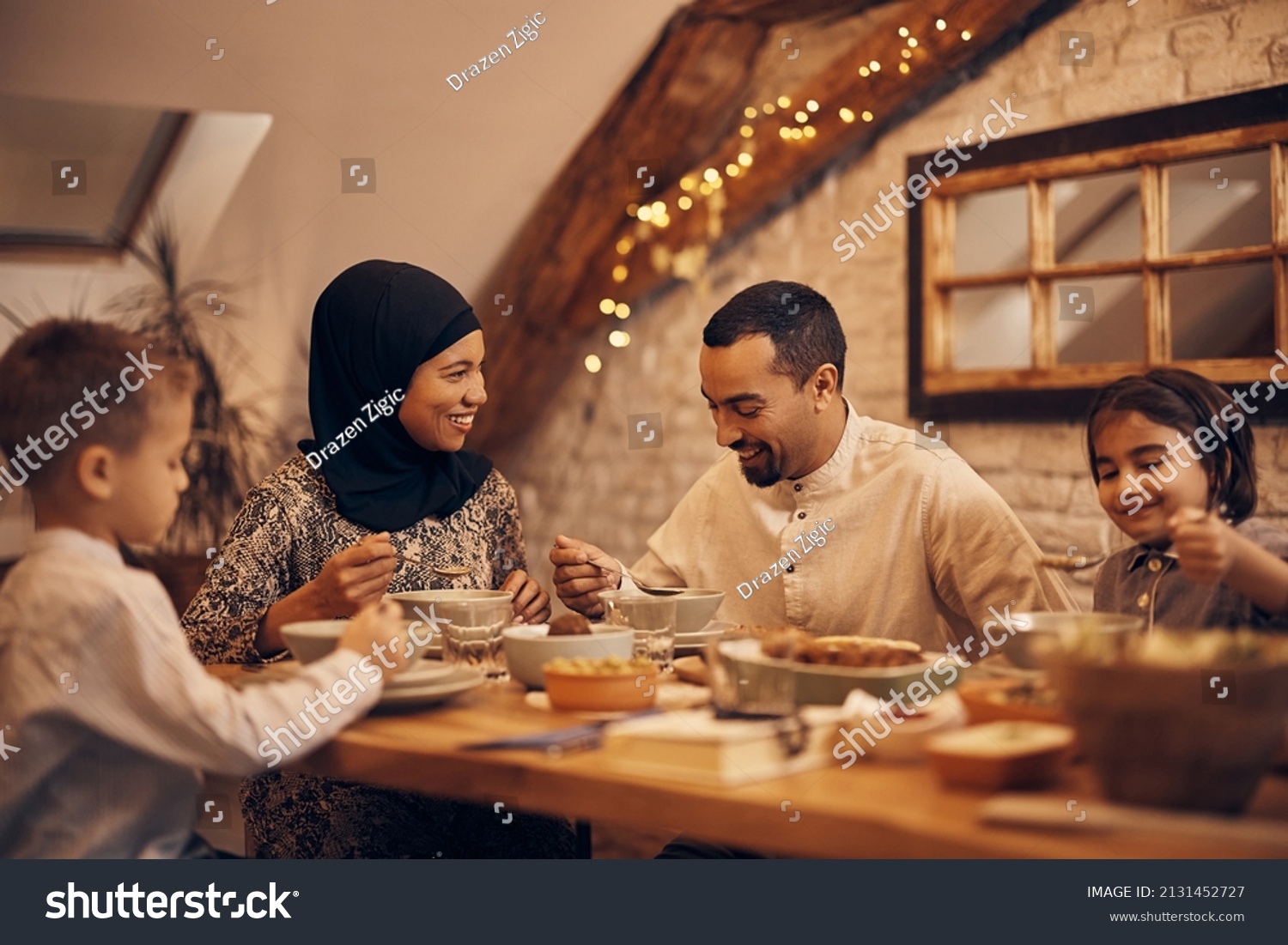 Happy Muslim parents having evening meal with their kids at dining table at home.  #2131452727