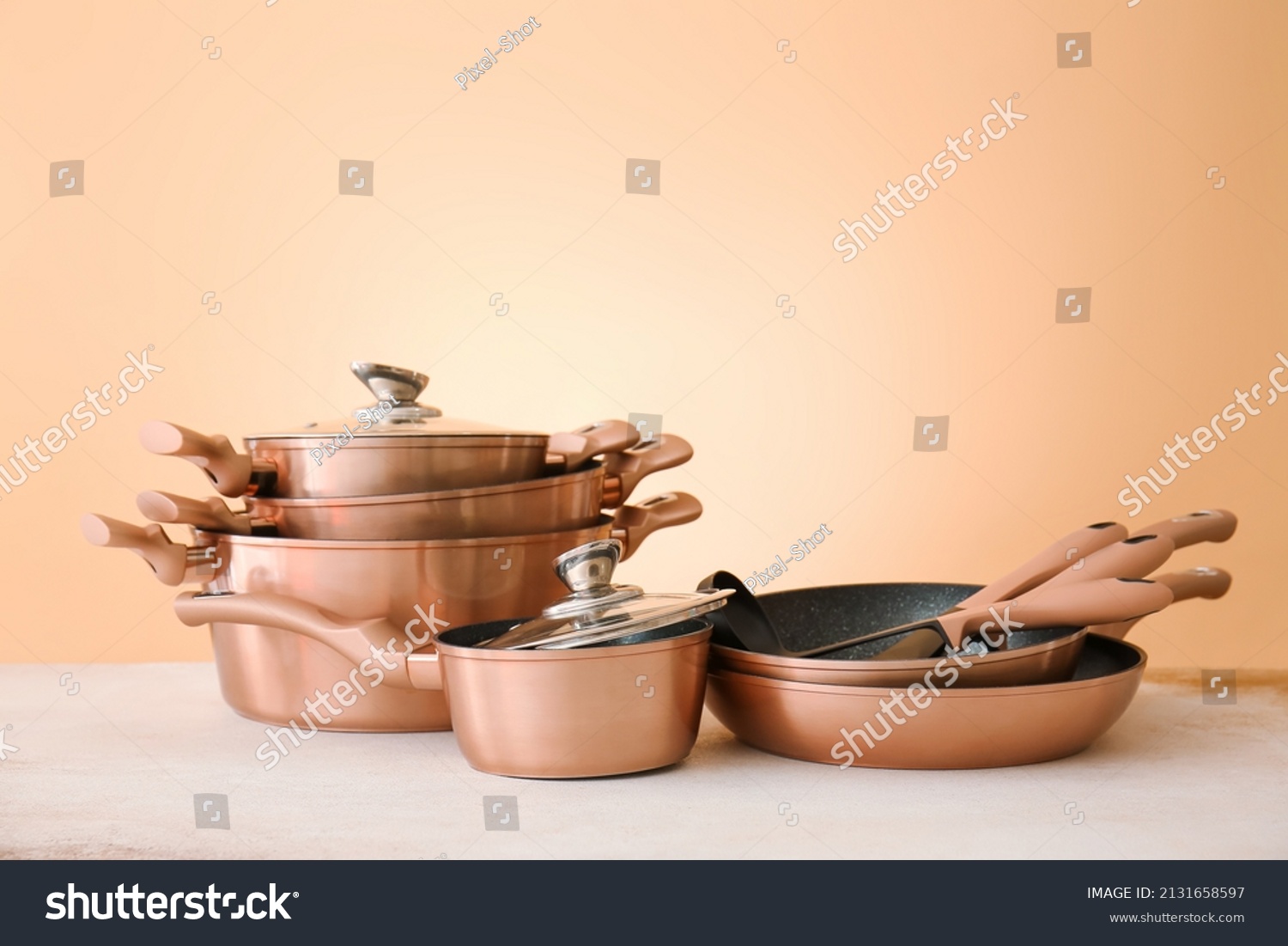 Set of copper utensils on table against color background #2131658597