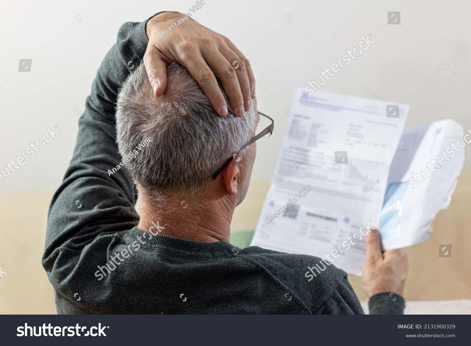 Worried   middle-aged man reading unexpected news in paper document. He is confused and astonished by unbelievable news: high bill tax invoice, debt notification, bad financial report, money problem #2131900329