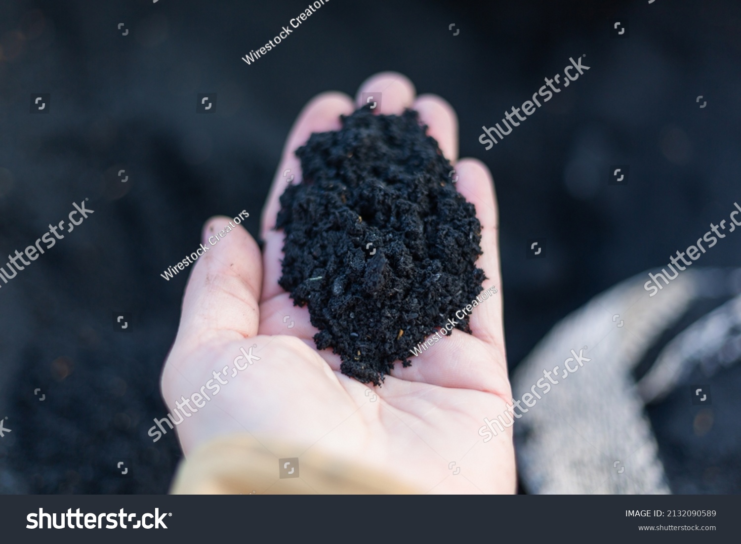 A top view of black Organic composted soil amendments in a hand #2132090589