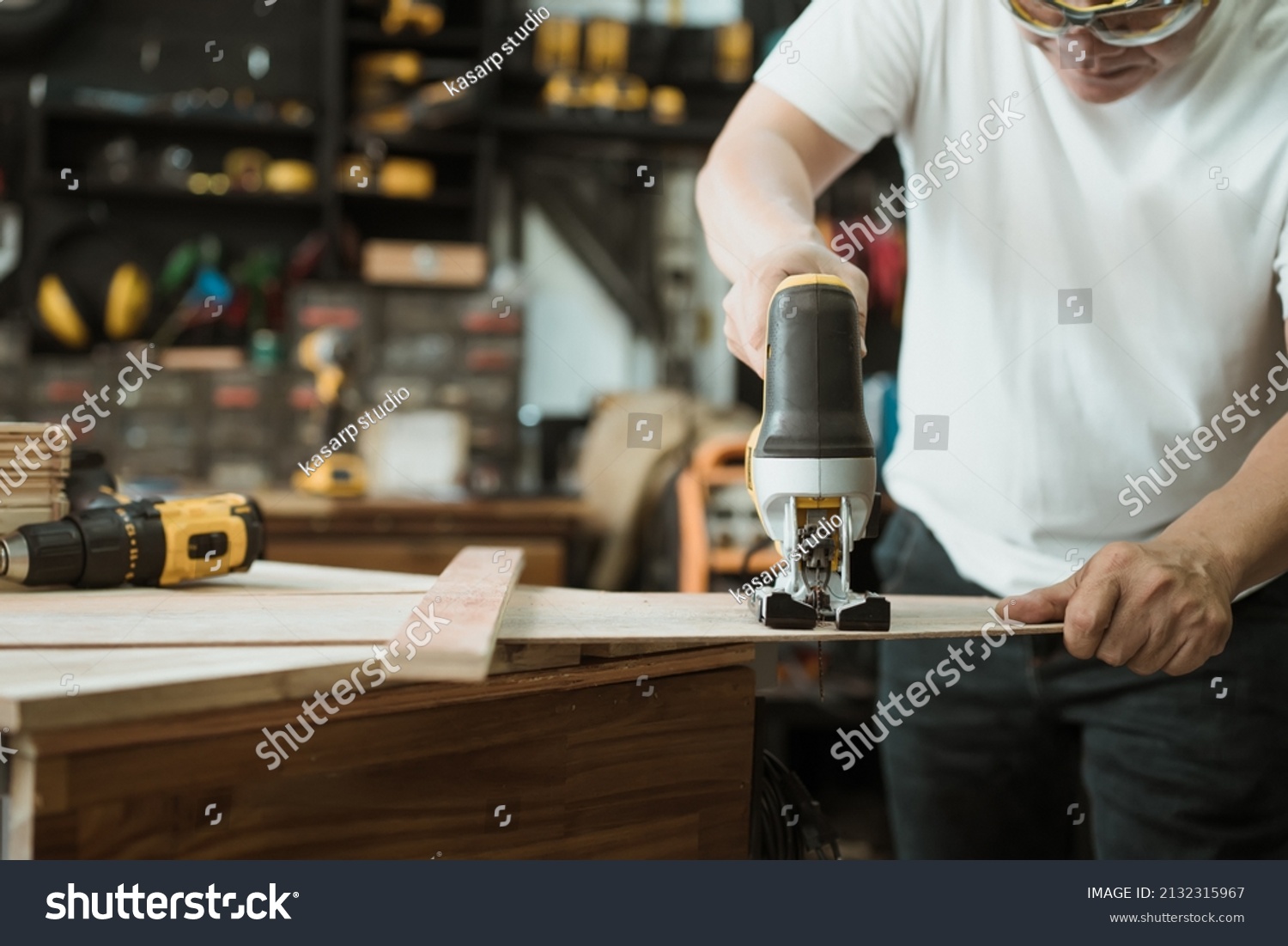 Carpenter cutting wooden with electric jigsaw in workshop, woodworking concept , selective focus #2132315967