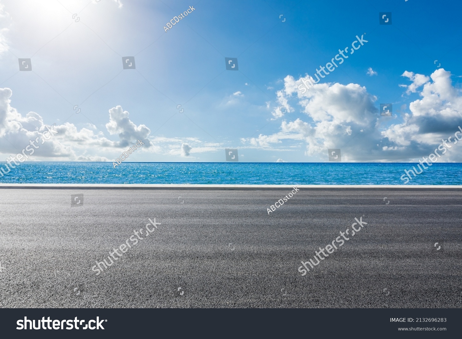 Empty asphalt road near the lake under blue sky #2132696283