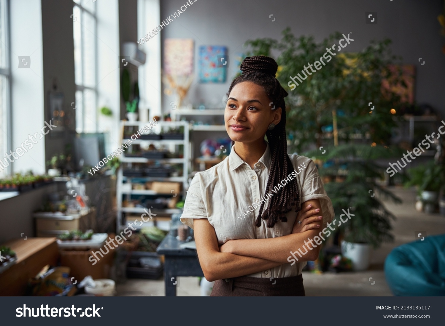 Smiling dreamy floral decorator with her arms folded looking away #2133135117