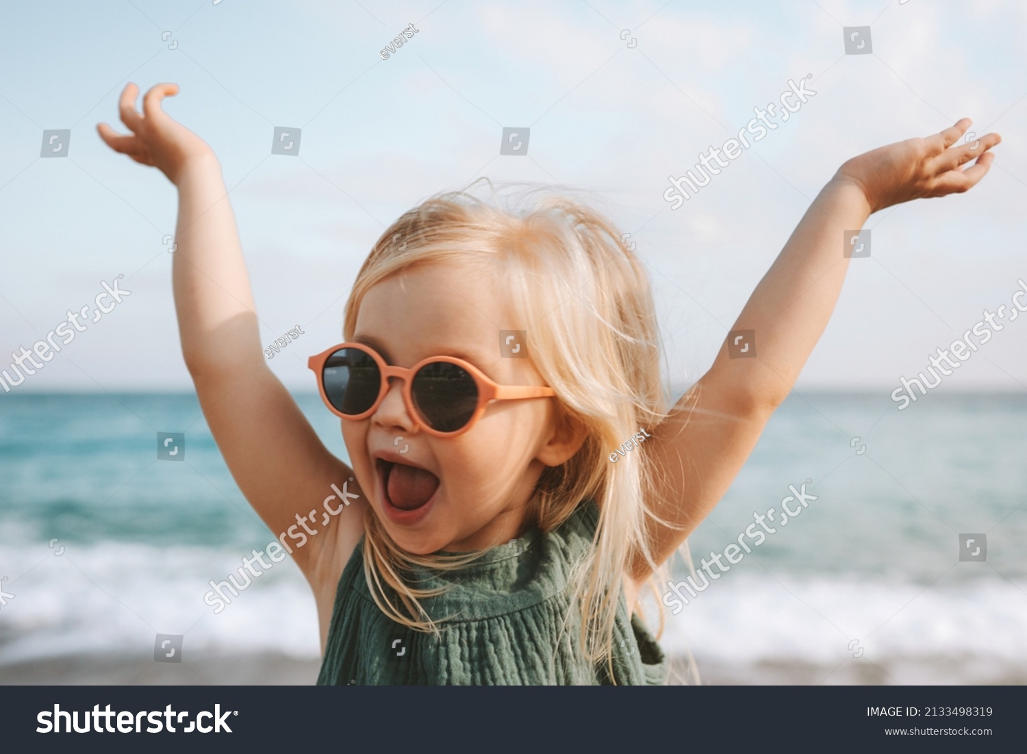 Funny kid girl playing outdoor surprised emotional child in sunglasses 3 years old baby raised hands family vacations  #2133498319