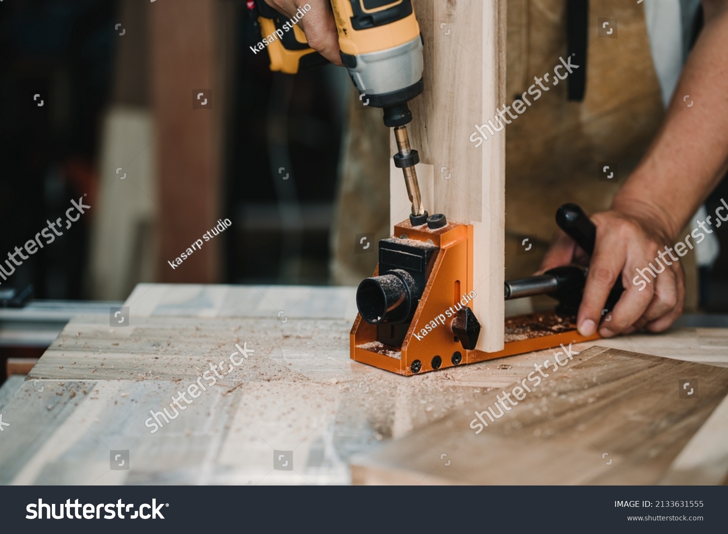 carpenter use drill bit and centering dowel jig or pocket hole jig tool to make strong joints on wooden plate. woodworking concept.selective focus. #2133631555