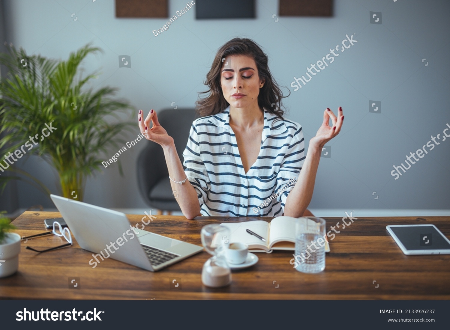Calm female executive meditating taking break at work for mental balance, mindful businesswoman feeling relief and no stress doing yoga at work ignoring avoiding stressful job and paperwork in office #2133926237