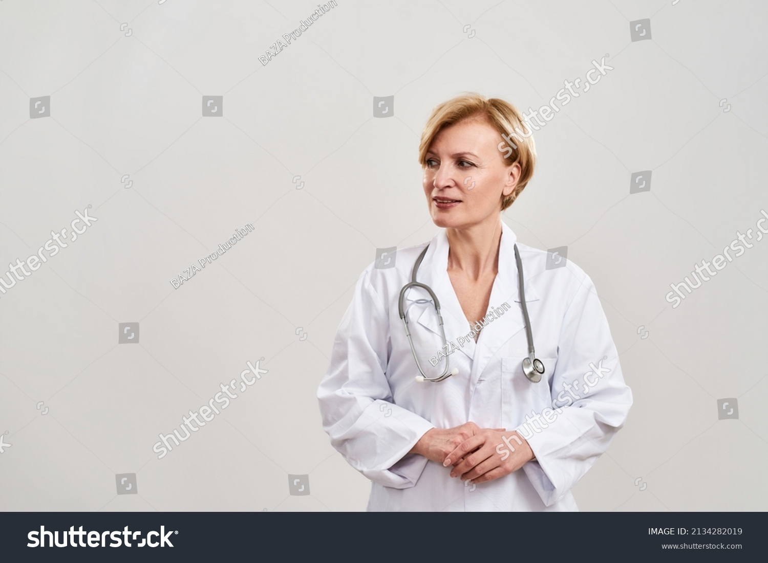 Partial image of focused female doctor looking away. Caucasian woman with stethoscope wearing white coat. Concept of medical and health care. Isolated on white background. Studio shoot. Copy space #2134282019