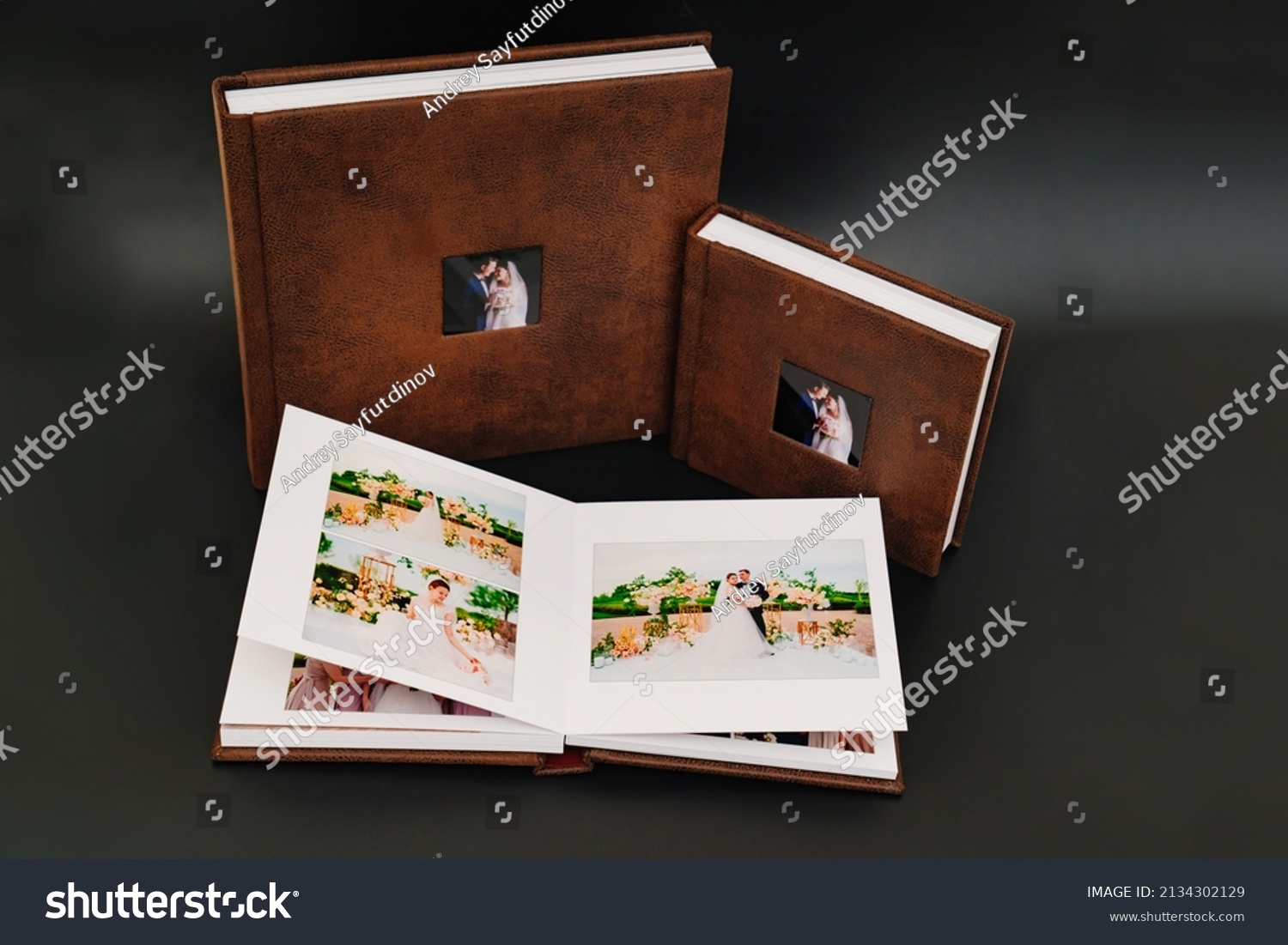 wedding photobooks in brown leather binding with photos on the cover. high-quality and expensive photo and printing products. services of a professional photographer and designer. on black background #2134302129