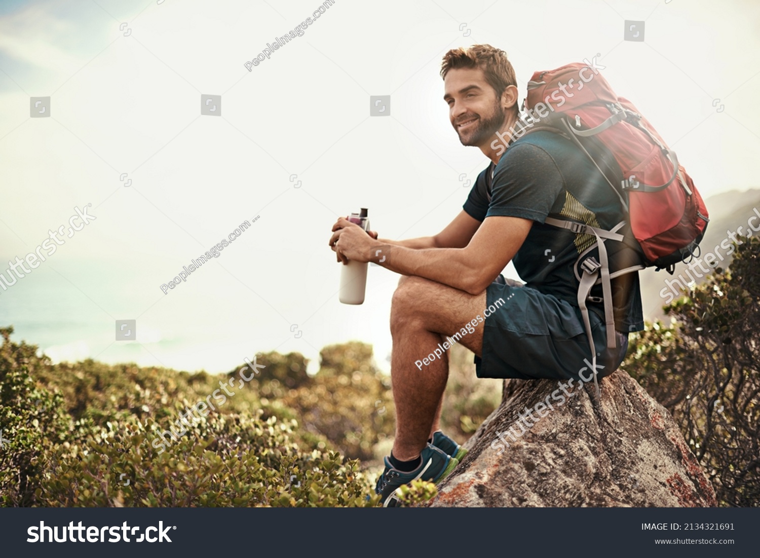 The perfect day to be out in nature.... Shot of a young man taking a water break while out hiking. #2134321691