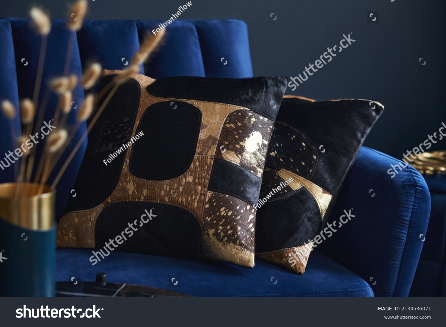 Stylish close up on the elegant pillow in the glamour living room interior. Golden home decorations and creative personal accesories. Dark blue wall. Template. Copy space. #2134536071