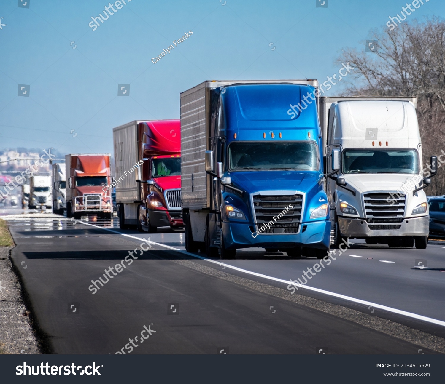 Horizontal shot of a long convoy of trucks on an interstate highway.

 #2134615629