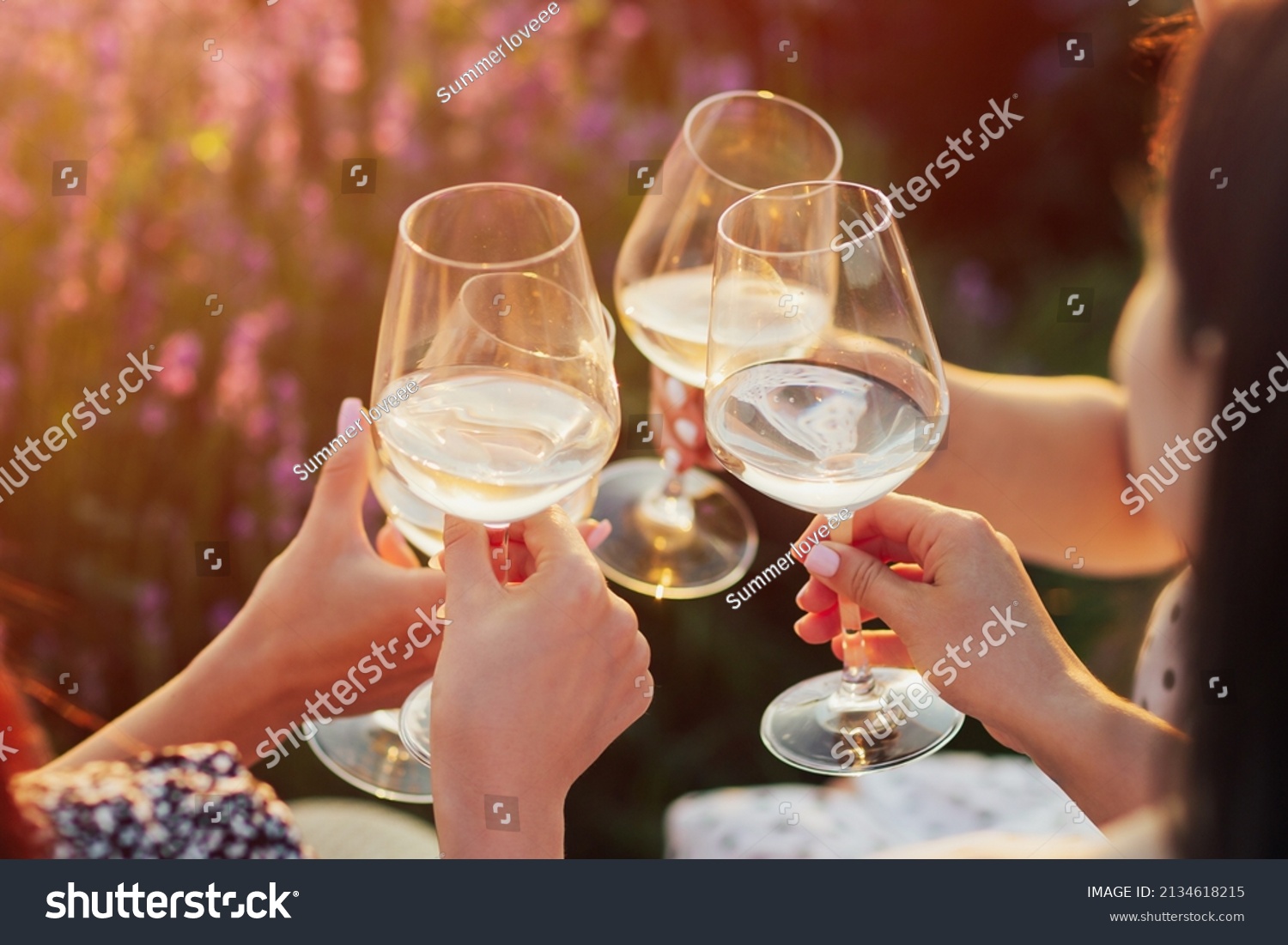 A group of girlfriends raise a toast with glasses of white colored wine on a sunset. Close shot. #2134618215