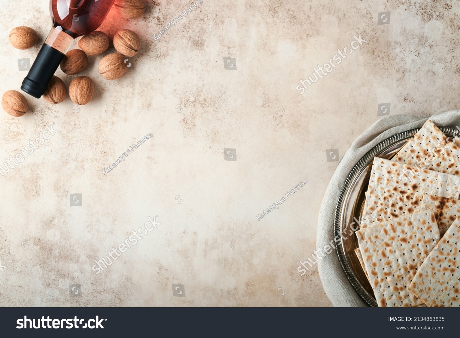 Passover celebration concept. Matzah, red kosher and walnut. Traditional ritual Jewish bread on sand color old concrete background. Passover food. Pesach Jewish holiday. #2134863835