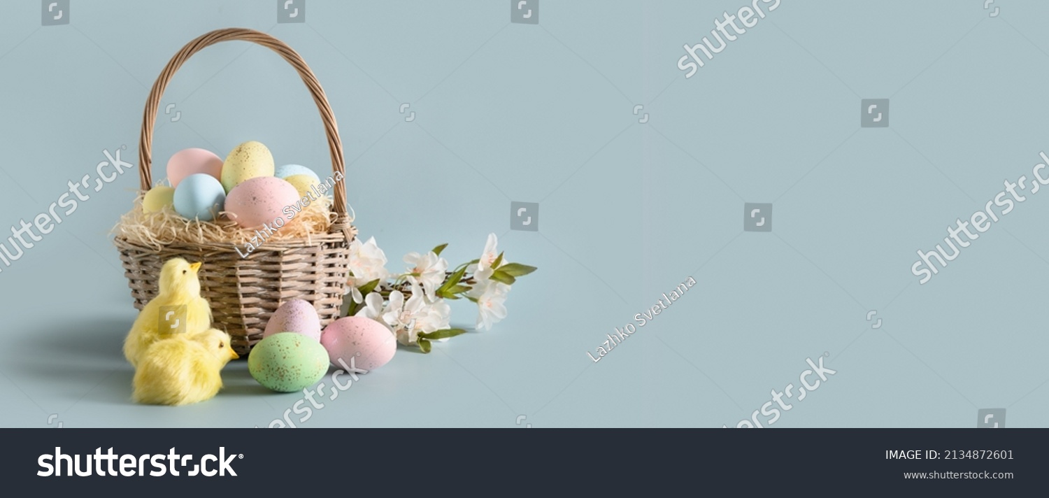 Easter wicker basket with pastel eggs for Happy holiday and celebration on blue background. Banner. Greeting card. #2134872601