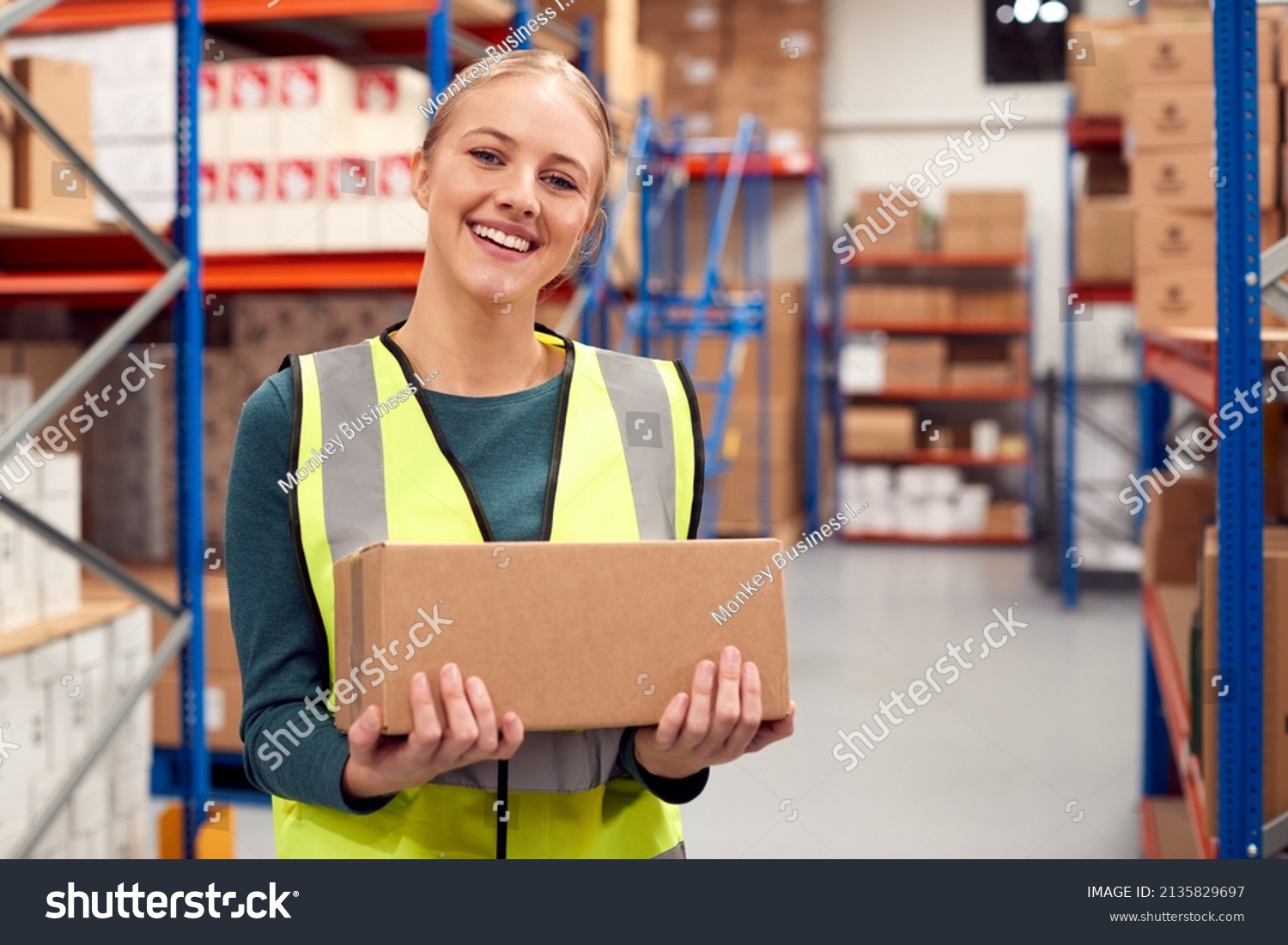 Portrait Of Female Worker Holding Box Inside Warehouse #2135829697