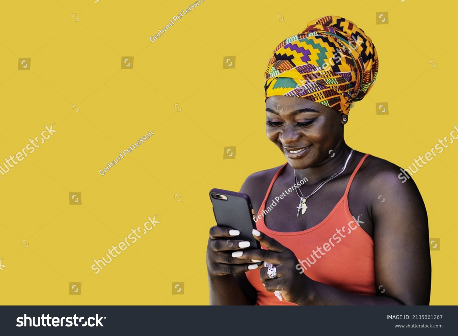 Ghana woman with African colorful headdress standing and chatting with mobile phone, illustrating the wireless technology in today's society #2135861267