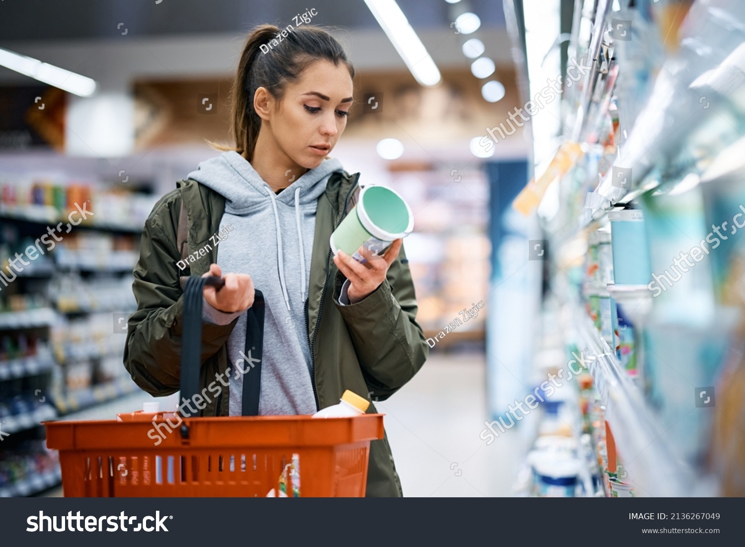 Young woman buying diary product and reading food label in grocery store. #2136267049