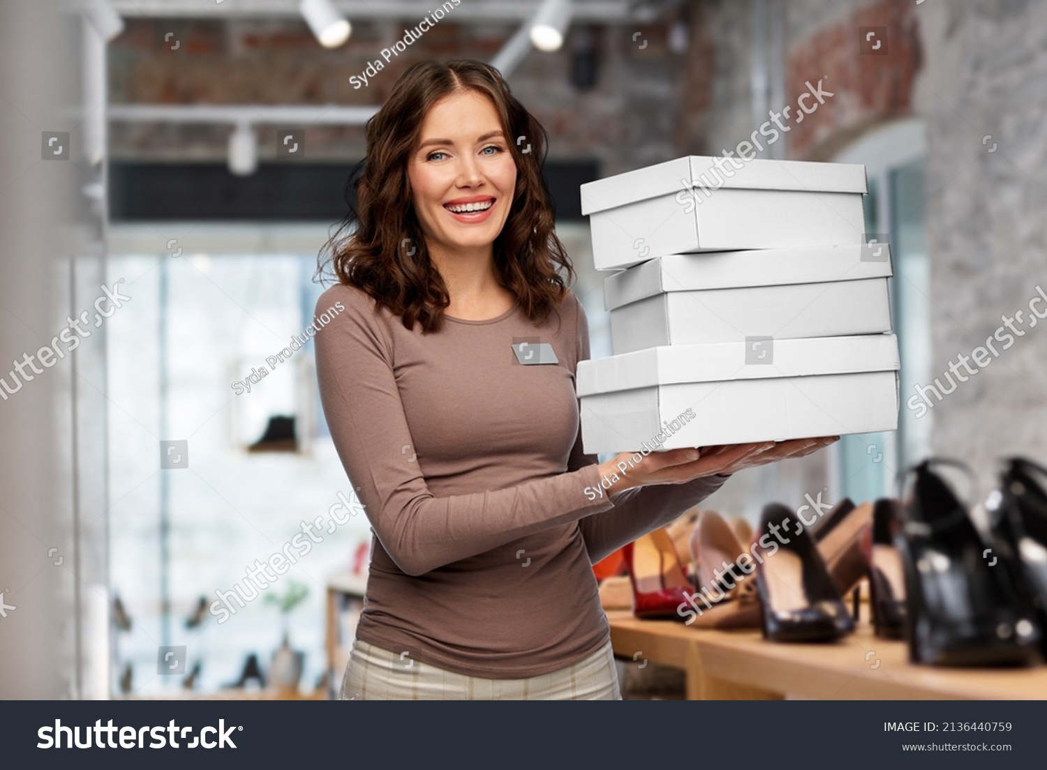 sale, shopping and business concept - happy female shop assistant or saleswoman holding three shoe boxes over store background #2136440759