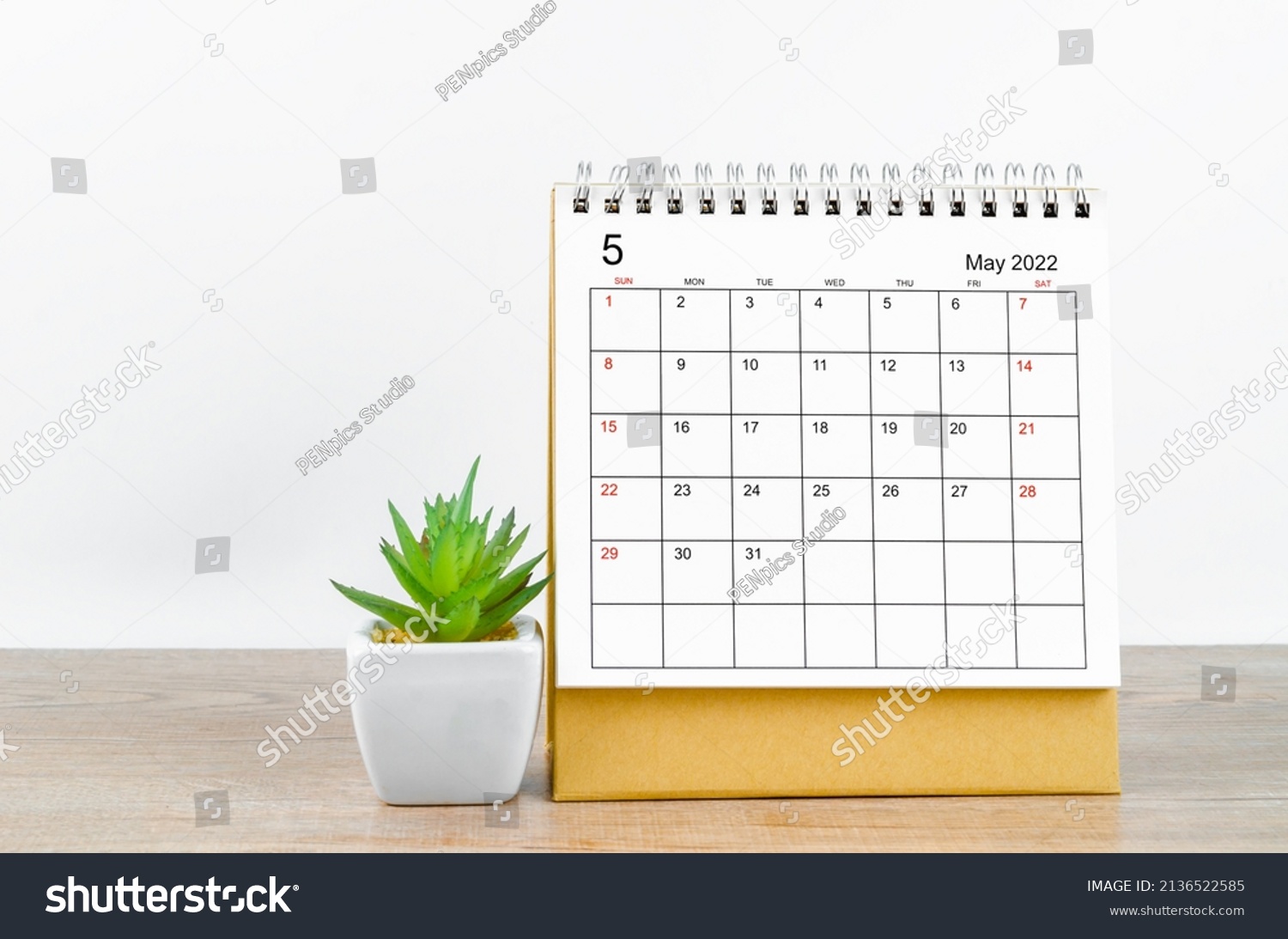 The May 2022 desk calendar with plant on wooden table. #2136522585