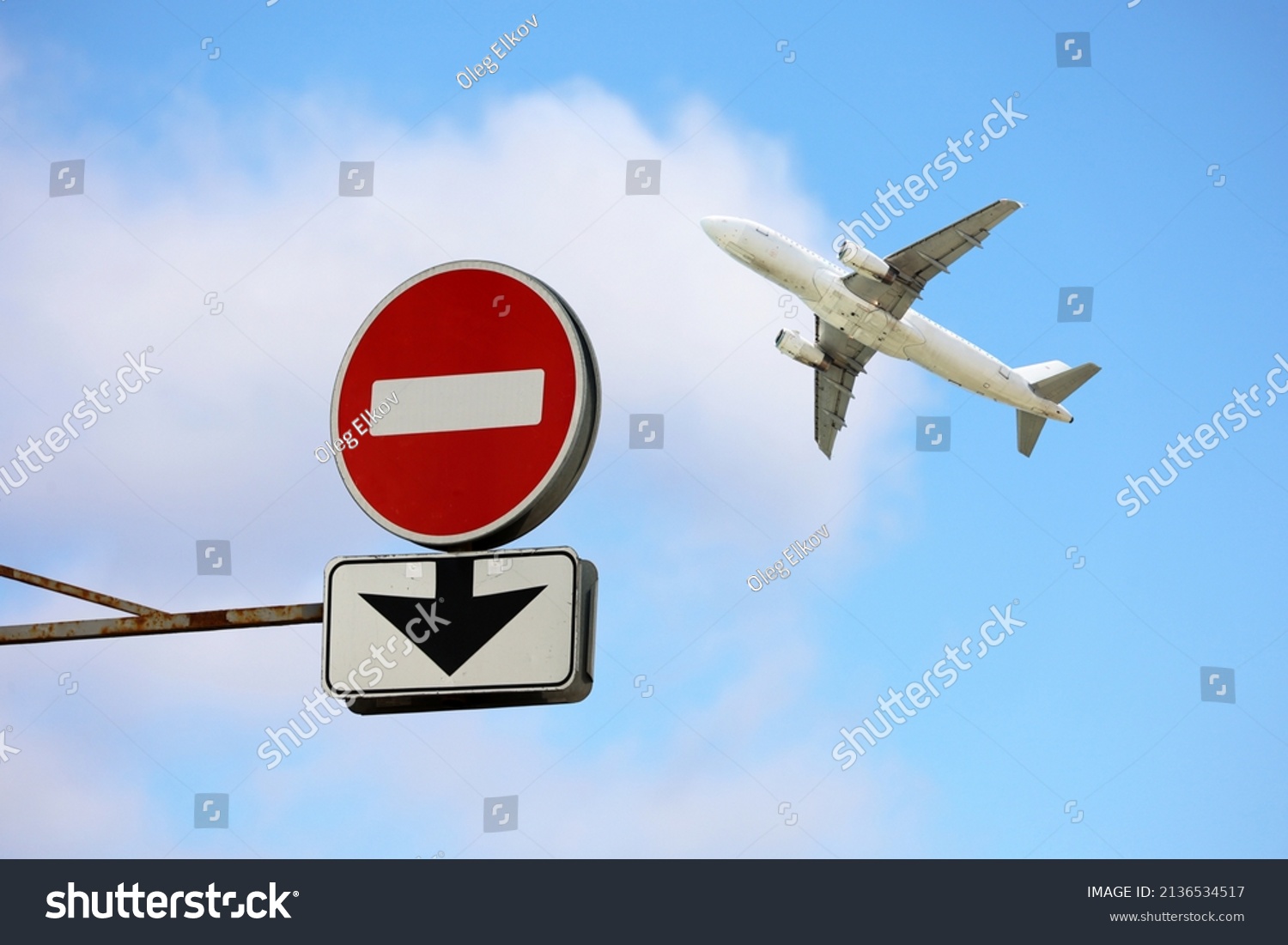 Stop sign with down arrow and airplane in blue sky. Concept of band on flights over Europe from Russia, sanctions due to the russian special military operation in Ukraine #2136534517