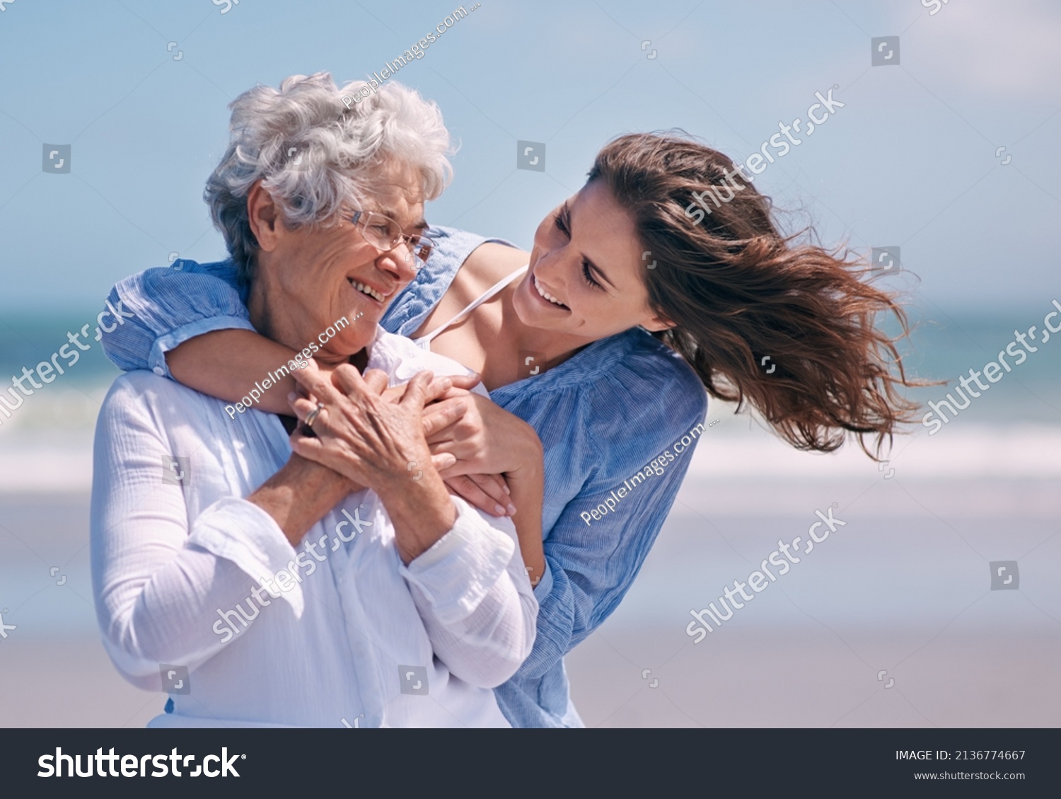 Taking time out to show some tenderness. Shot of a beautiful young woman and her senior mother on the beach. #2136774667