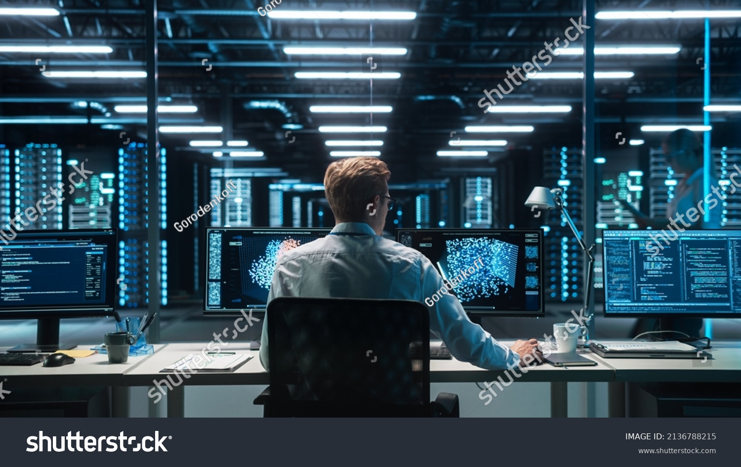 Software Developer Works with AI Analysis on his Computer with Two Monitors. Developer Coding while Looking at the Display of Computer. Modern Evening Dark Office. Back view. #2136788215