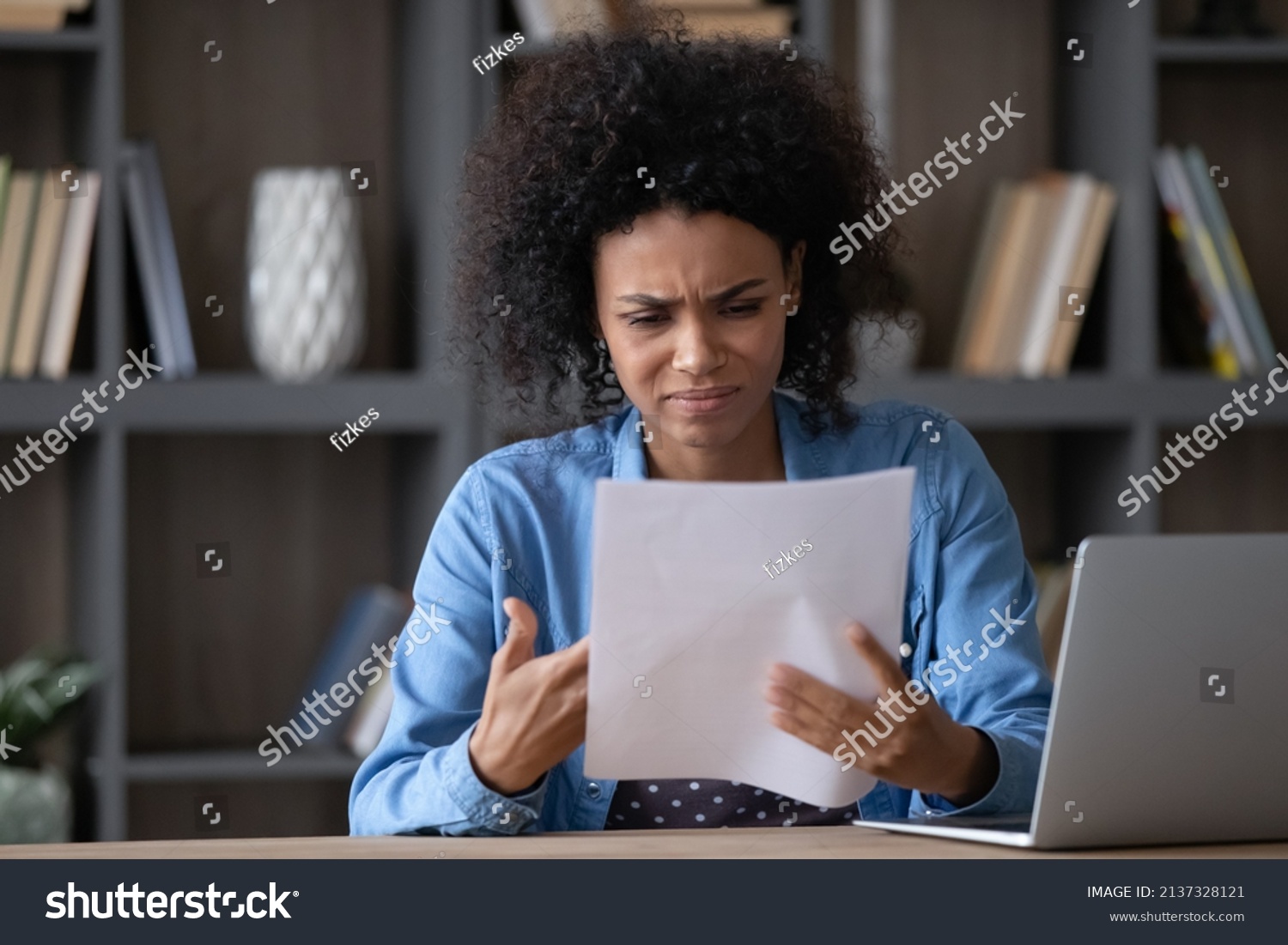 Annoyed frustrated African student girl receiving paper letter, rejection notice from university, feeling stress. Upset young Black employee woman reading document with bad dismissal news. #2137328121