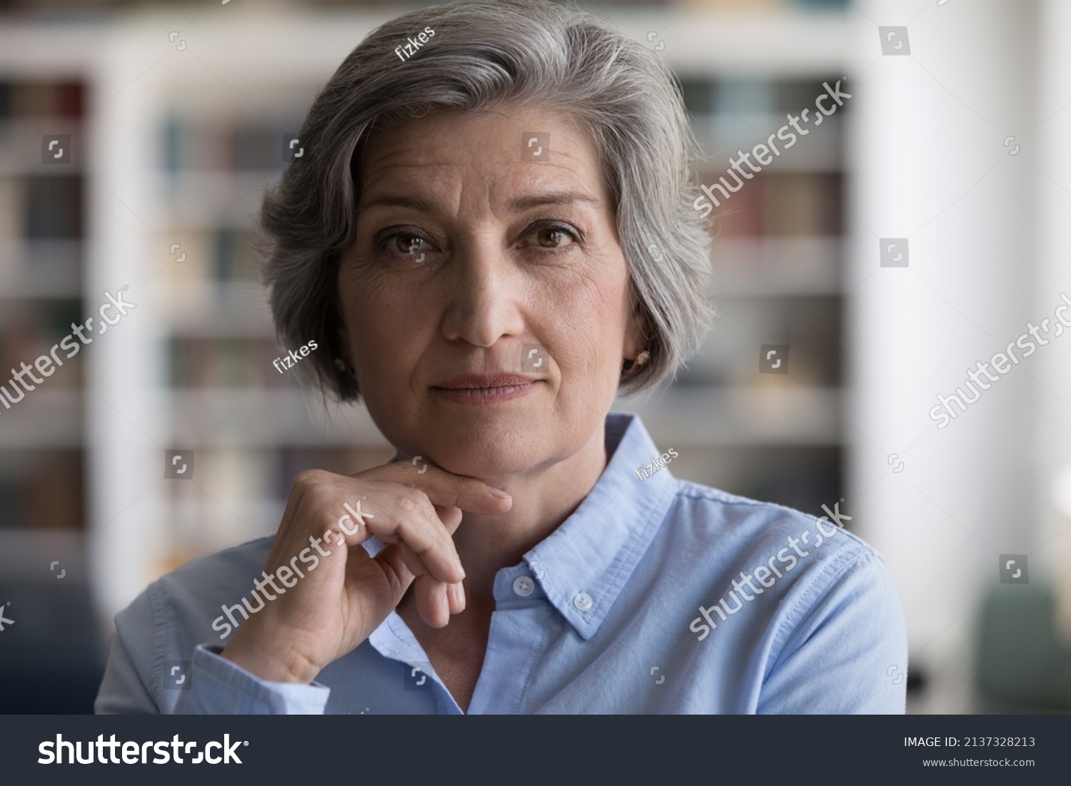 Close up head shot beautiful grey-haired woman touch chin with hand staring at camera, looks confident and serious, having elegant style, attractive appearance. Mature businesswoman portrait concept #2137328213