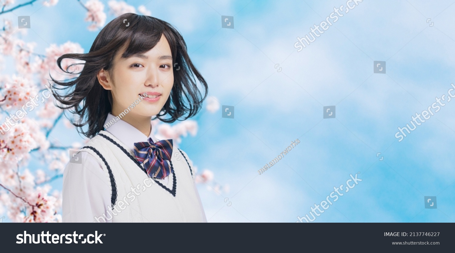 Young asian school girl blowing her hair in front of cherry blossoms. #2137746227