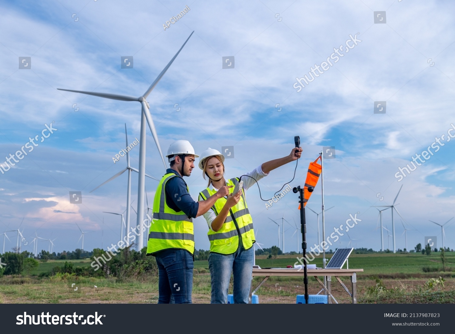 Engineers using meteorological or anemometer instrument collect data laptop to measure the wind speed, temperature,humidity and solar cell system on wind turbine station is sustainable energy concept #2137987823