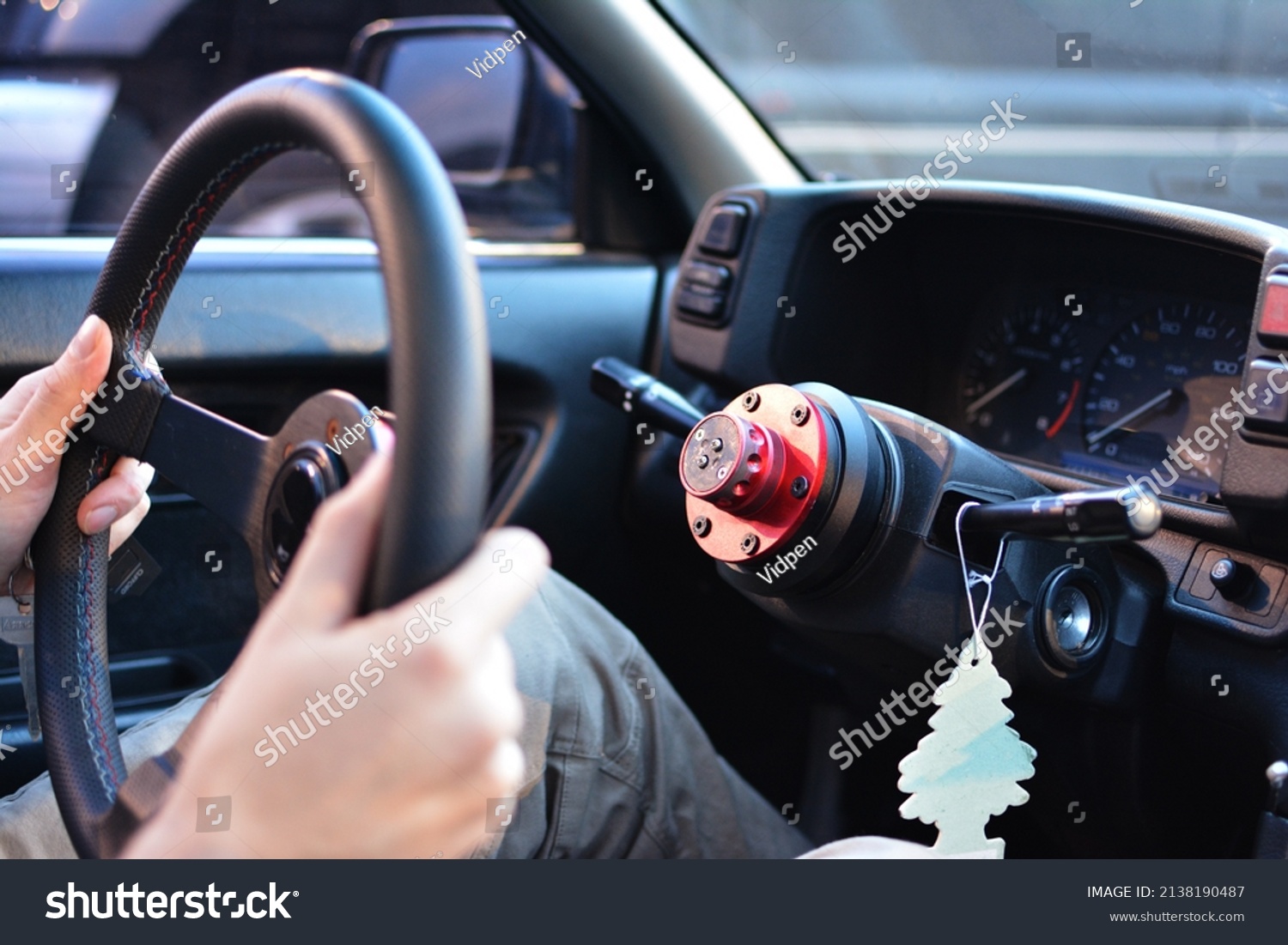 Person removing steering wheel from stock to protect car from theft. Close up with hands holding steering wheel detached from steering column in older car to prevent crime #2138190487
