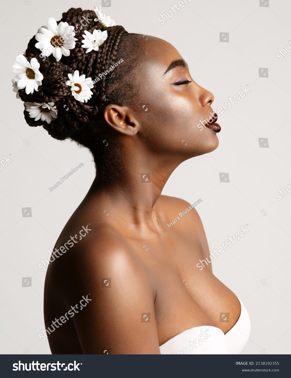 Beauty Profile of African American Woman with White Chamomile Flowers in Black Hair Braids. Fashion Portrait of Dark Skin Model over White. Wedding Make up and Bride Cornrows Hairstyle #2138192355
