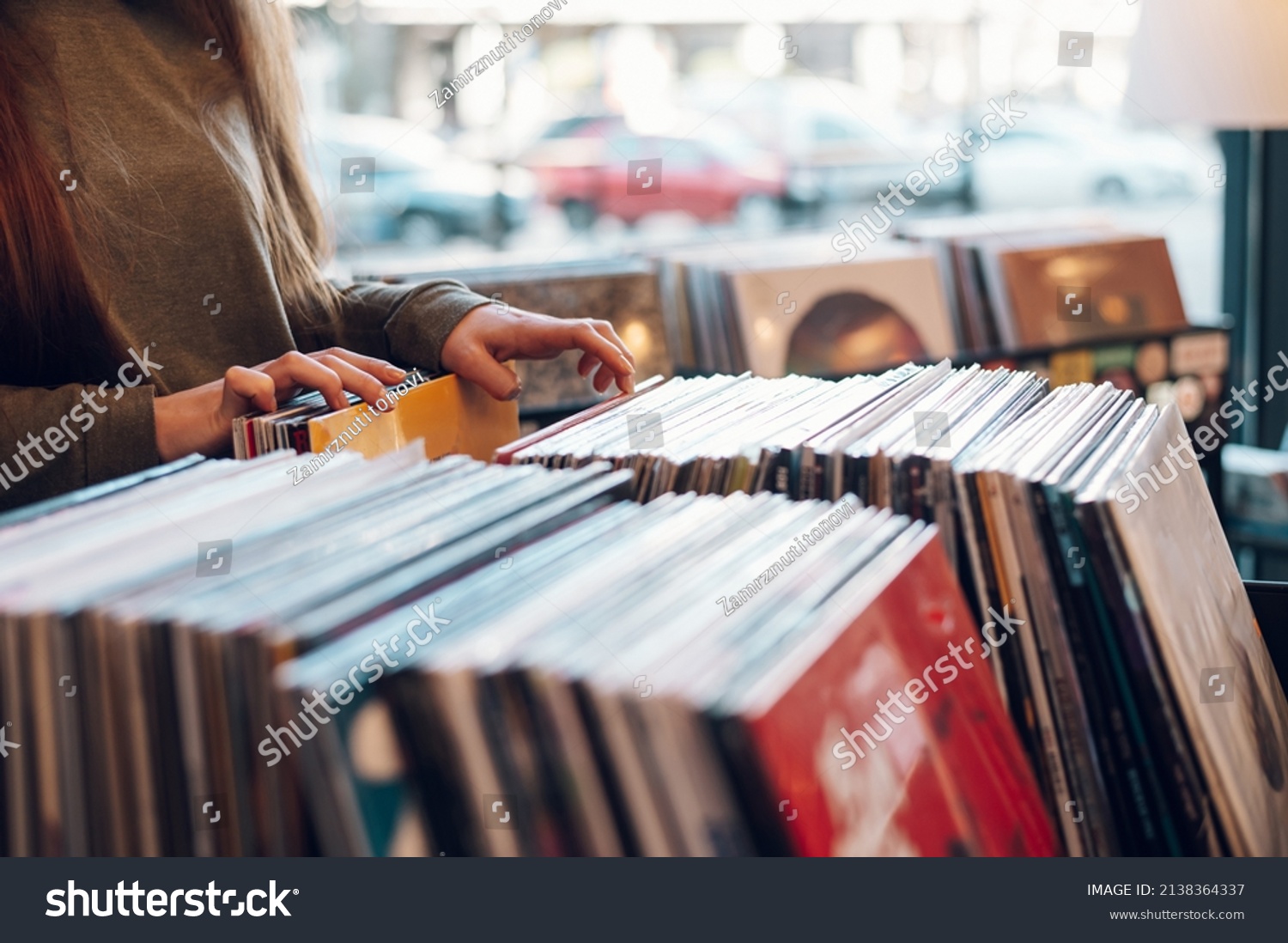 Close shot of a woman hands browsing records in the vinyl record store. Audiophile and music lover. Vintage Vinyl LP In Records Shop. #2138364337