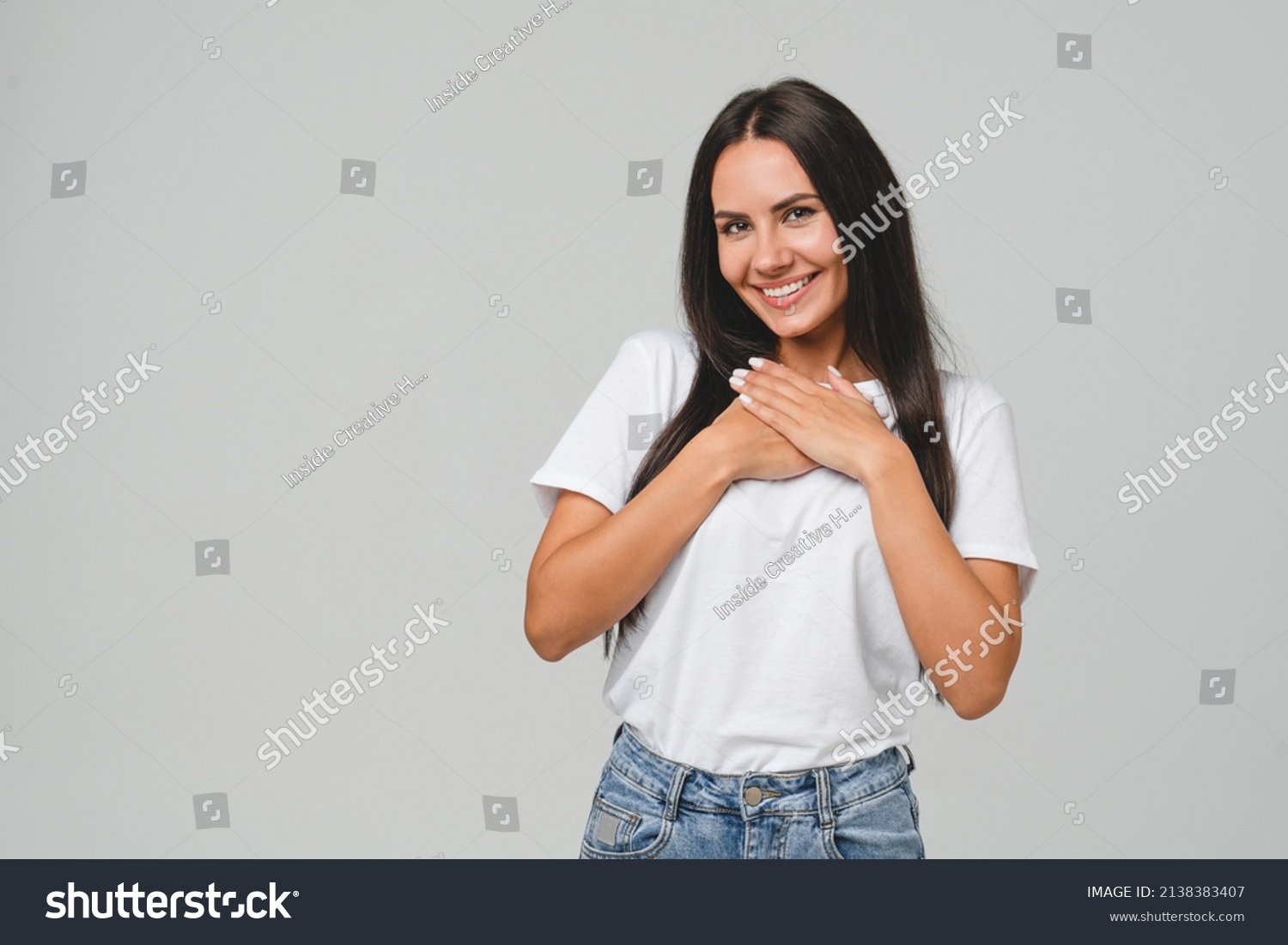 Touched pleased with a compliment cheerful happy caucasian young woman in white T-shirt isolated in grey background. Praise recommendation, sweet heart #2138383407