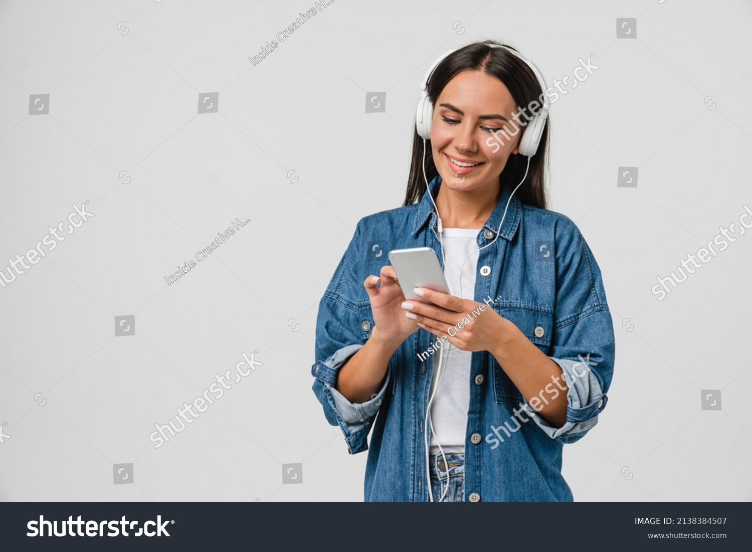 Smiling caucasian young woman listening to the podcast e-book music song singer rock band in headphones earphones, choosing sound track on cellphone isolated in white background #2138384507