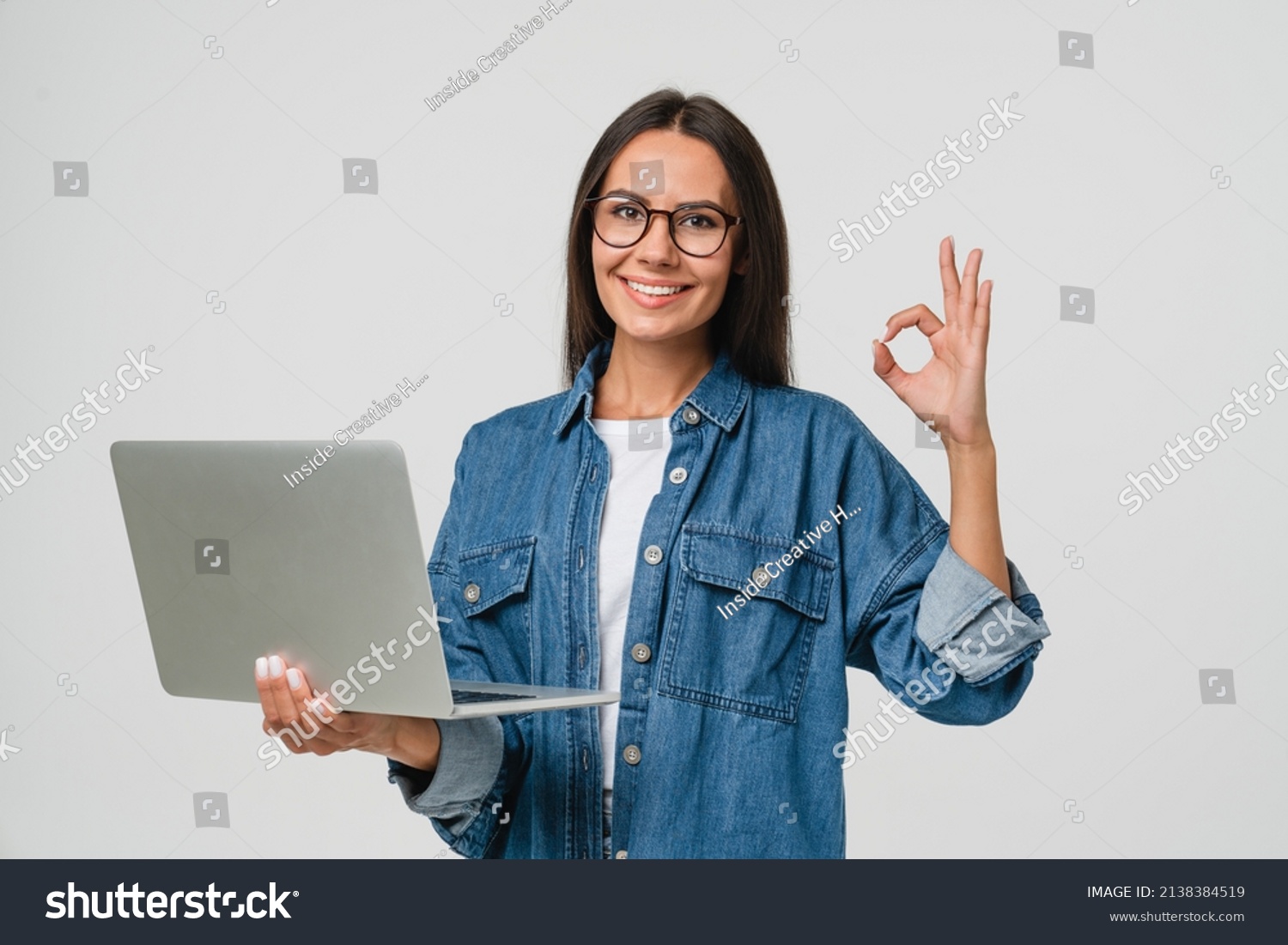 Young smiling caucasian student freelancer woman using laptop for remote work, e-learning at university college, e-banking, online shopping, webinars showing okay gesture isolated in white background #2138384519