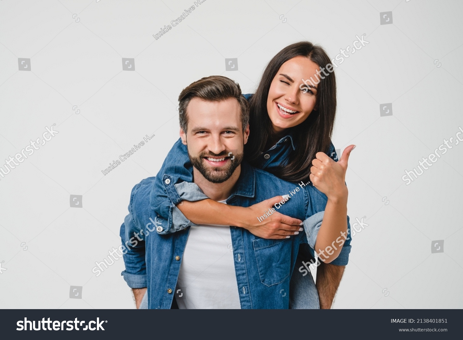 Young happy caucasian couple spouses girlfriend and boyfriend doing piggyback, dating, sharing love and passion showing thumb up isolated in white background #2138401851