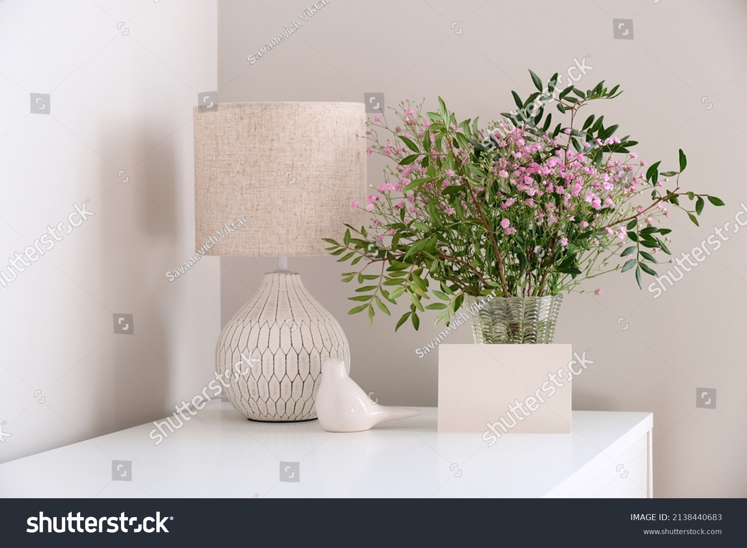 Cozy home desk table with lamp, bunch of spring flowers in vase, greeting card mockup. Hygge, boho style, scandinavian living room #2138440683