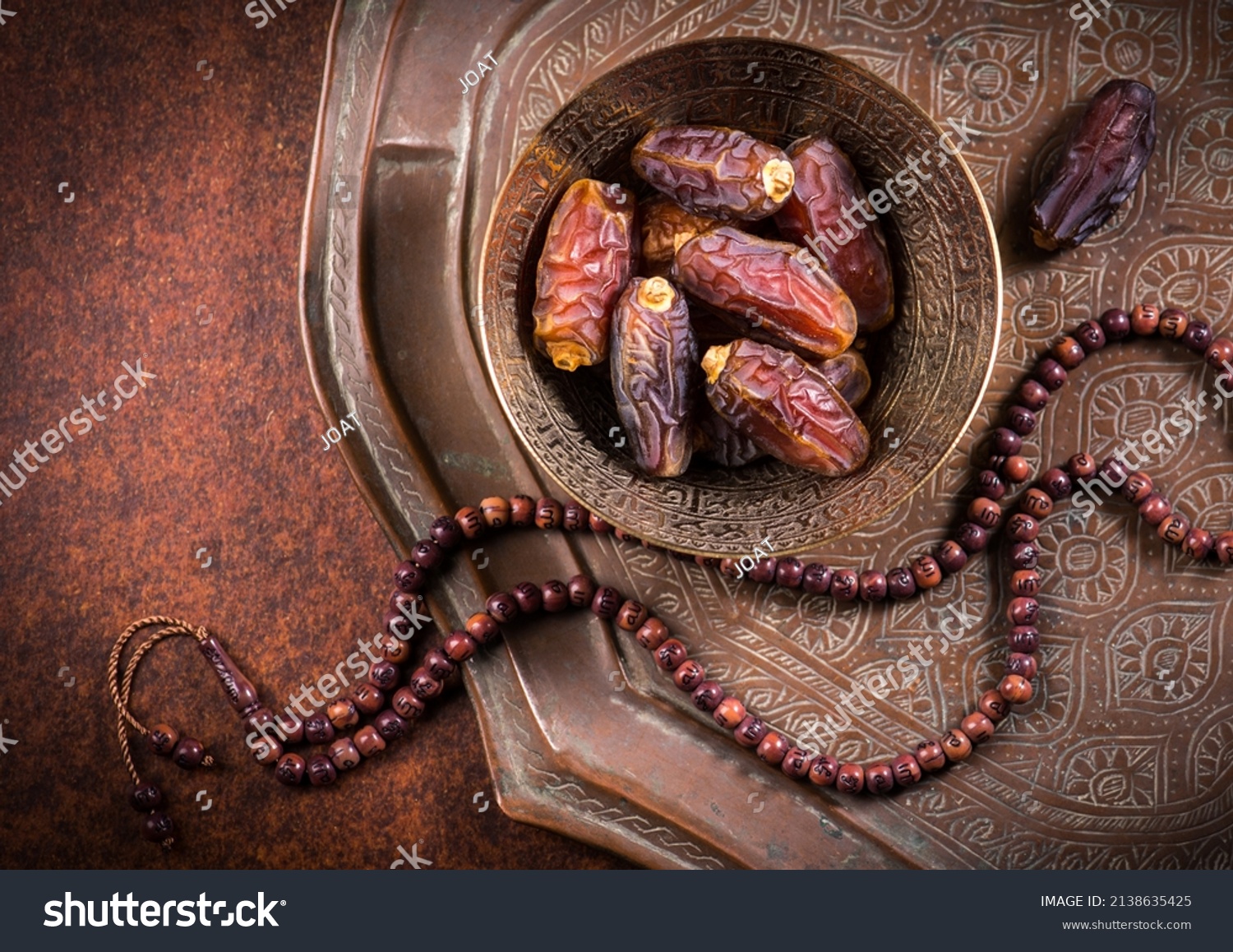 Arabian dates in an antique metal bowl with Islamic prayer beads. Ramadan Kareem- Muslim festival objects and background.
 #2138635425