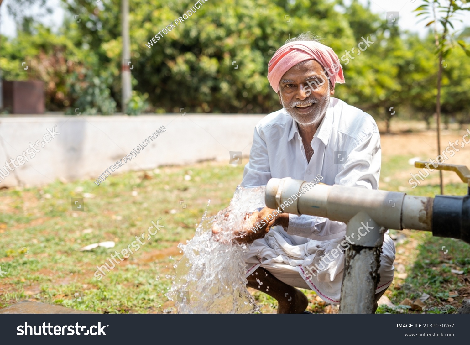 Happy Indian farmer after seeing water on borewell pipe at farmland - cocnept of happiness, poverty and water for agricultural works. #2139030267