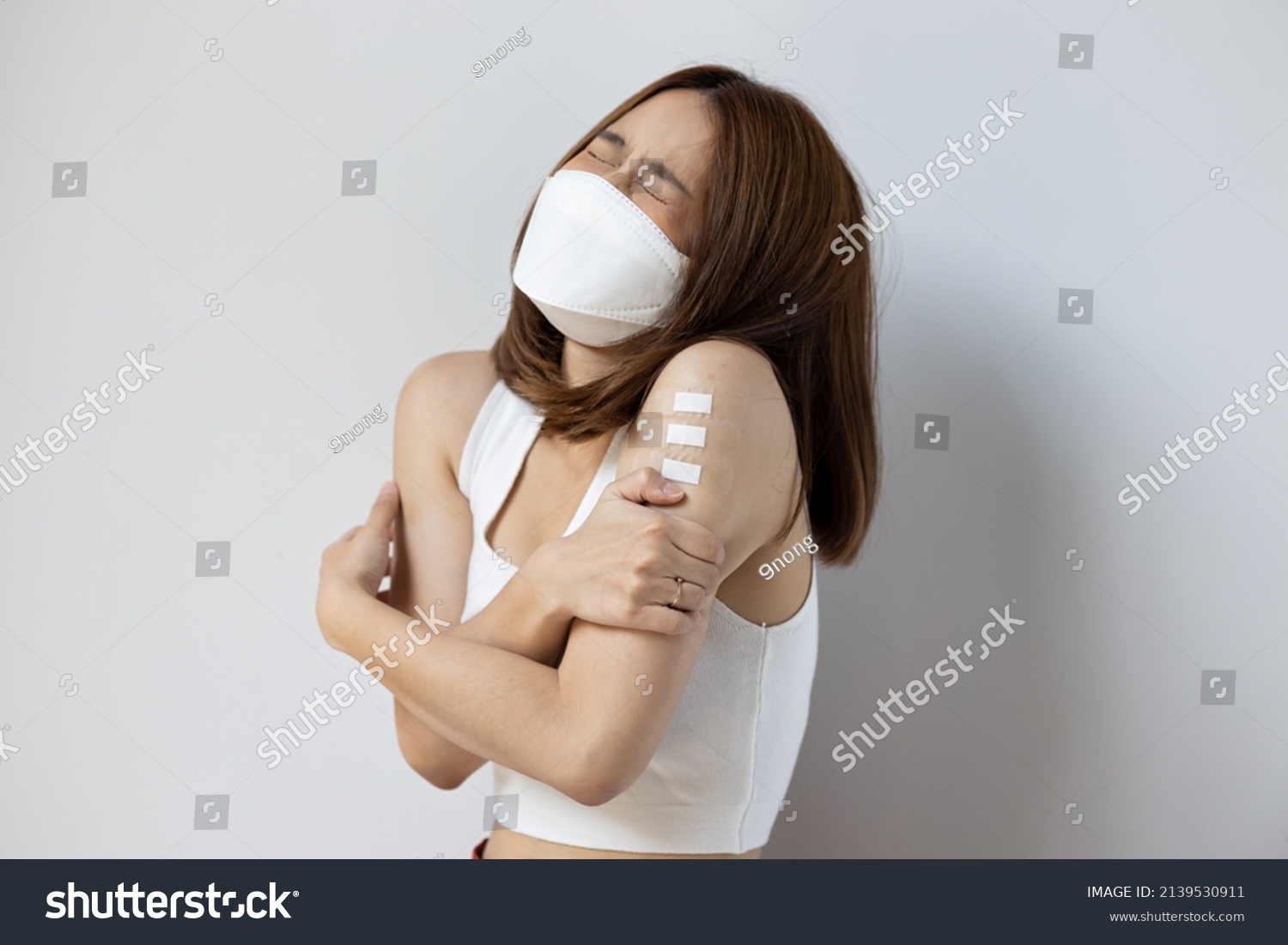 Concept image of fully vaccinated asian woman getting boosted with the first booster, experiencing headache, fever, adverse event side effect after vaccine booster shot #2139530911