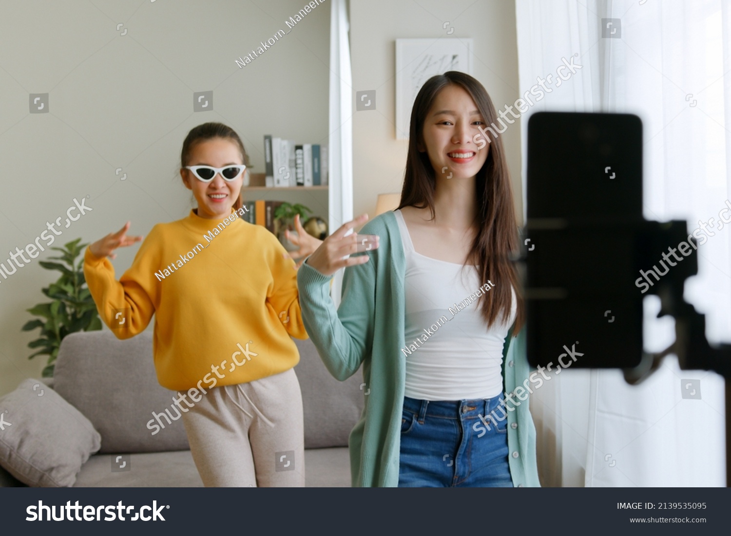 Asian young woman with her friend er created her dancing video by smartphone camera together To share video to social media application #2139535095