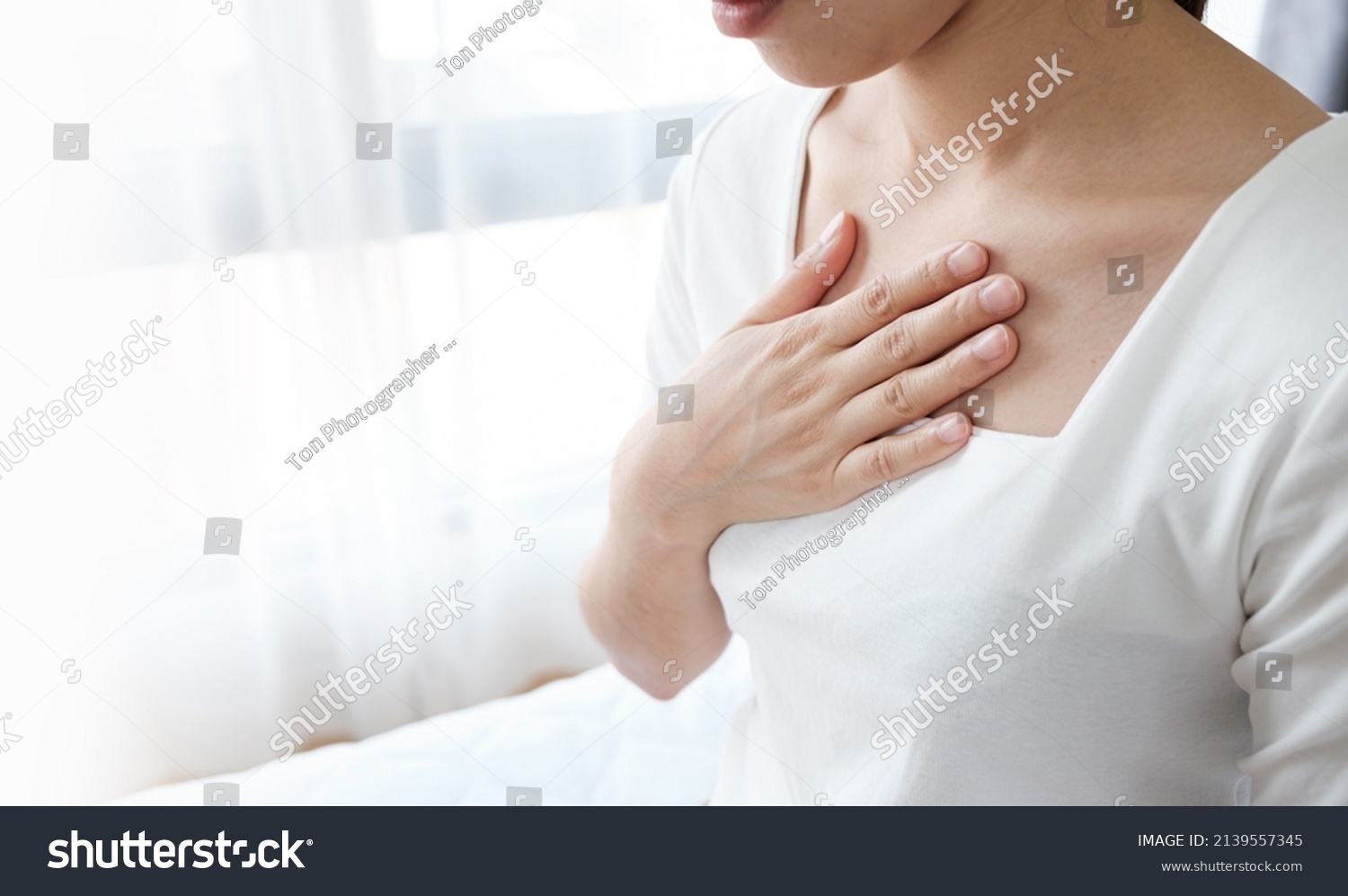 Young woman putting her hand on her chest. Having a pain in chest, Gastroesophageal Reflux Disease  have frequent belching. Healthcare medical concept.  #2139557345