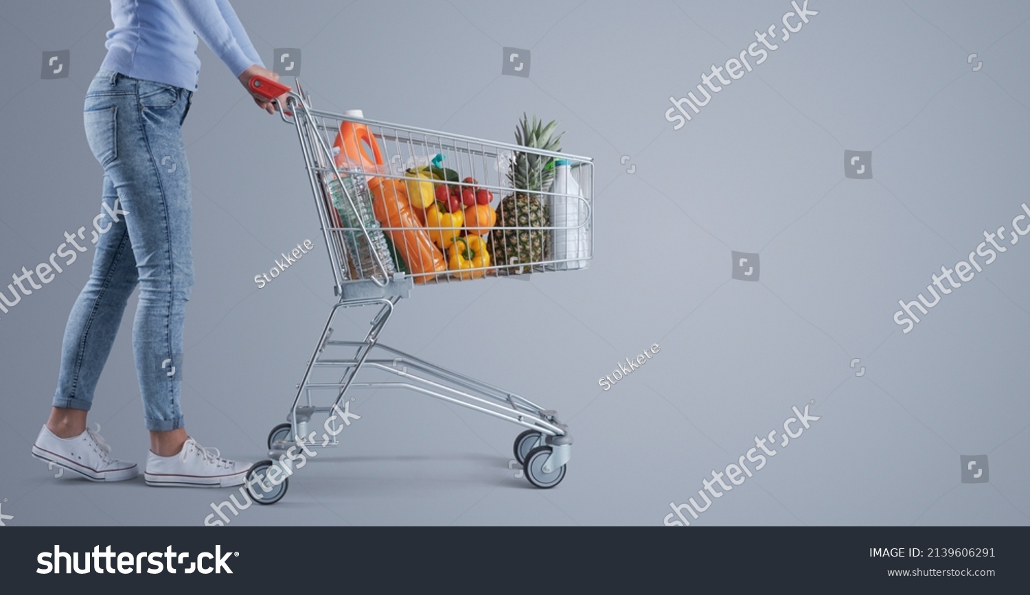 Young woman pushing a full shopping cart, supermarket and grocery shopping banner, blank copy space #2139606291